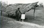 Native American man stands next to the Town Plaza sign