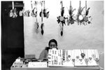 Native American woman sits behind table with jewelry and other crafts on display